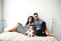 Happy young father, mother and cute baby boy lying on rustic bed
